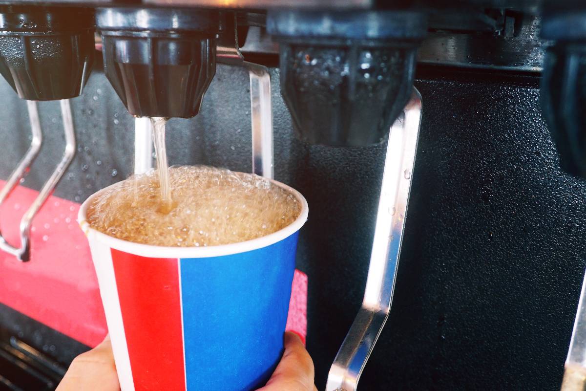 Man pouring cola fizzy drink at a self service machine. 