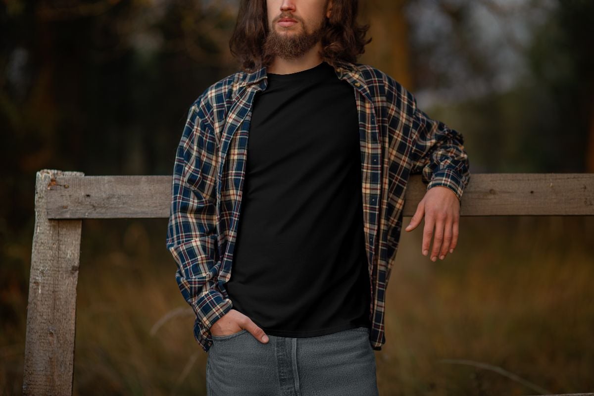 Man wearing a black shirt layered with flannel long sleeves.