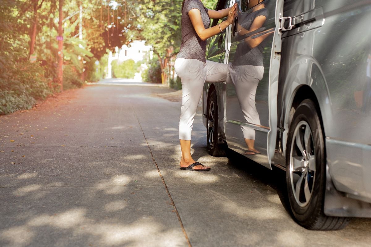 Woman in flip flops getting on the van.
