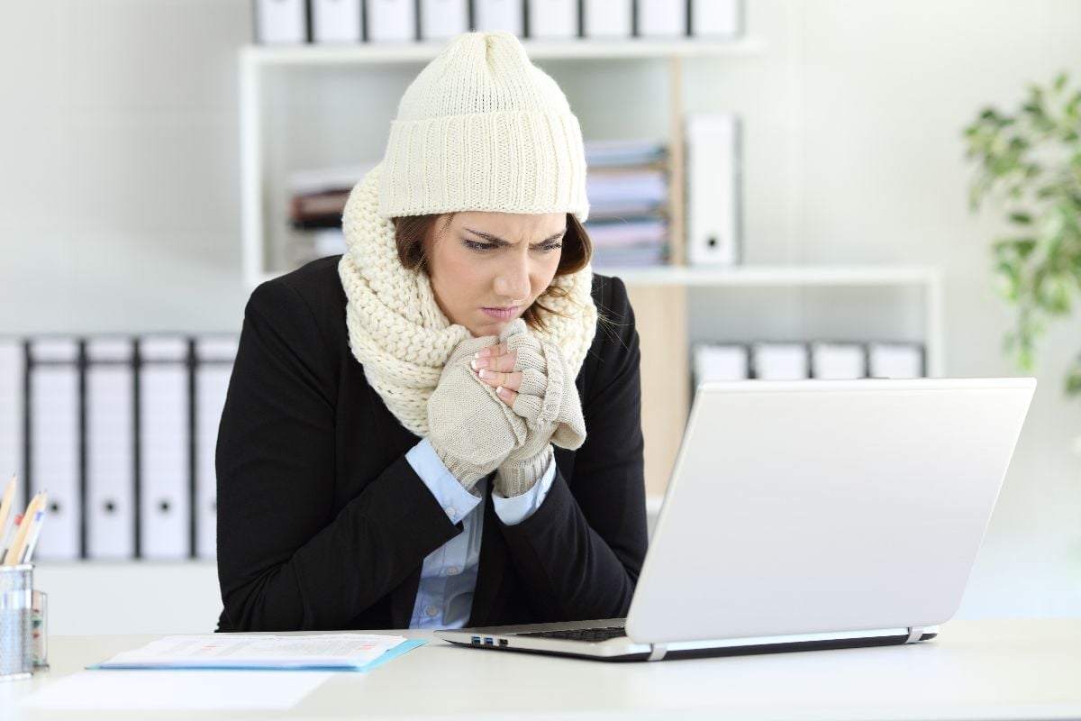 Cold executive working at office with a freezing air condition.