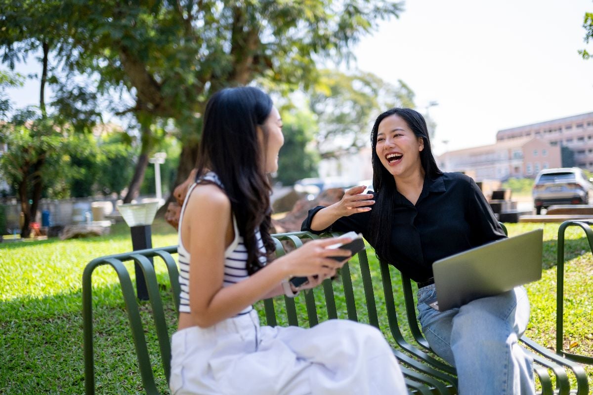 Two women chatting on a bench.