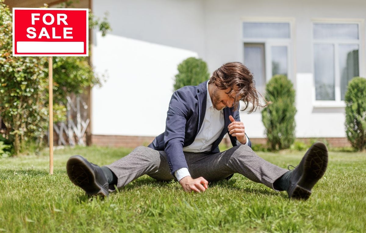 Angry property manager sitting on lawn in front of open house outside.
