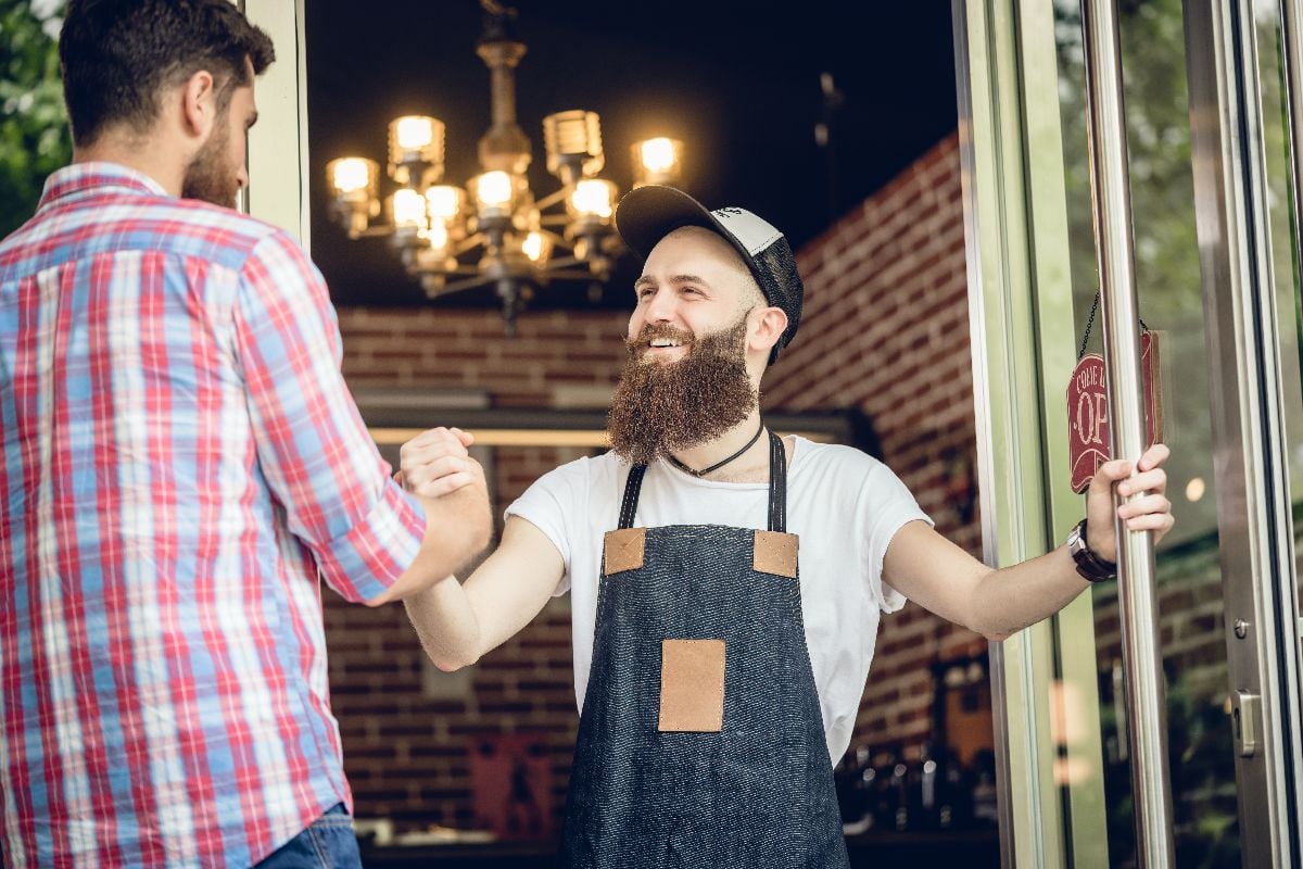 Barber greeting his customer at the entrance of hair salon.