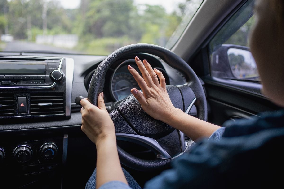 Woman pushing horn while driving.