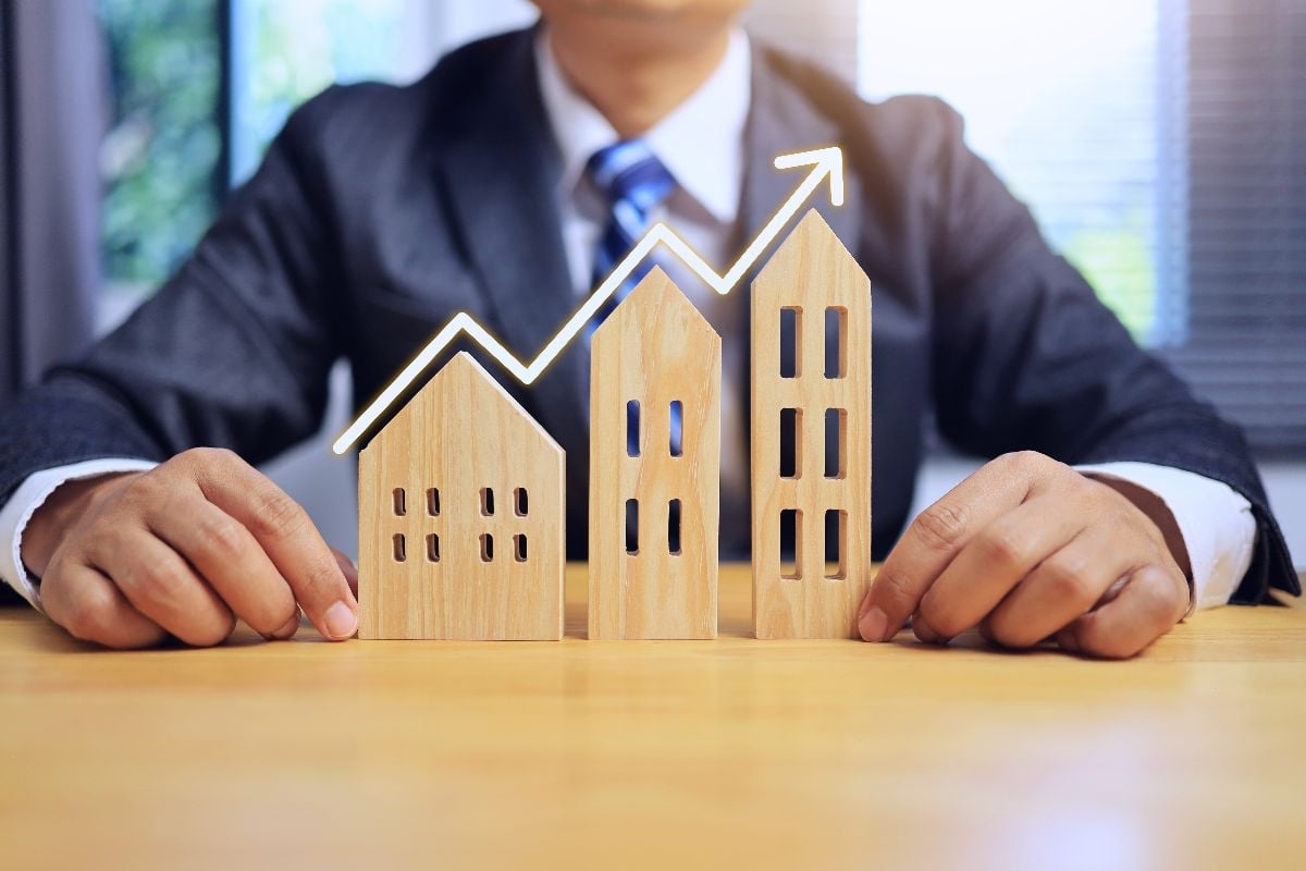 House business concept with businessman comparing three houses with an arrow above.