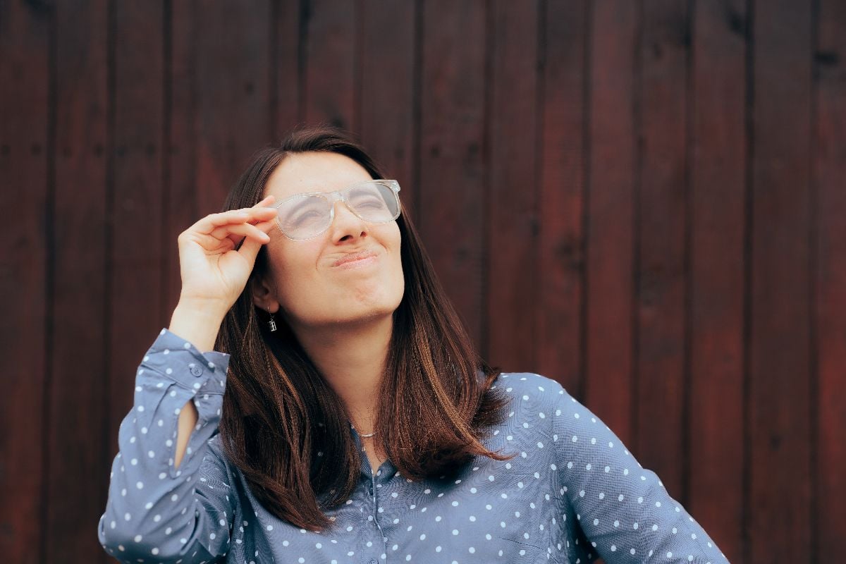 Woman with foggy eyeglasses looking up outdoors.