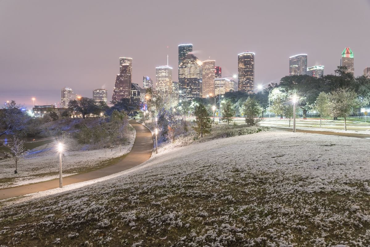 Downtown Houston at  twilight with big and fluffy snowflakes fell on meadow grass.