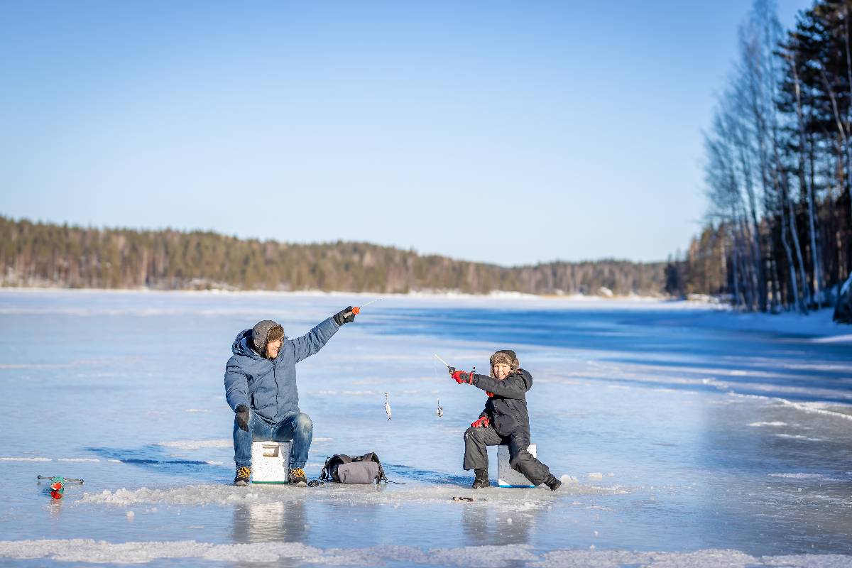 Father and son winter fishing at the frozen lake.