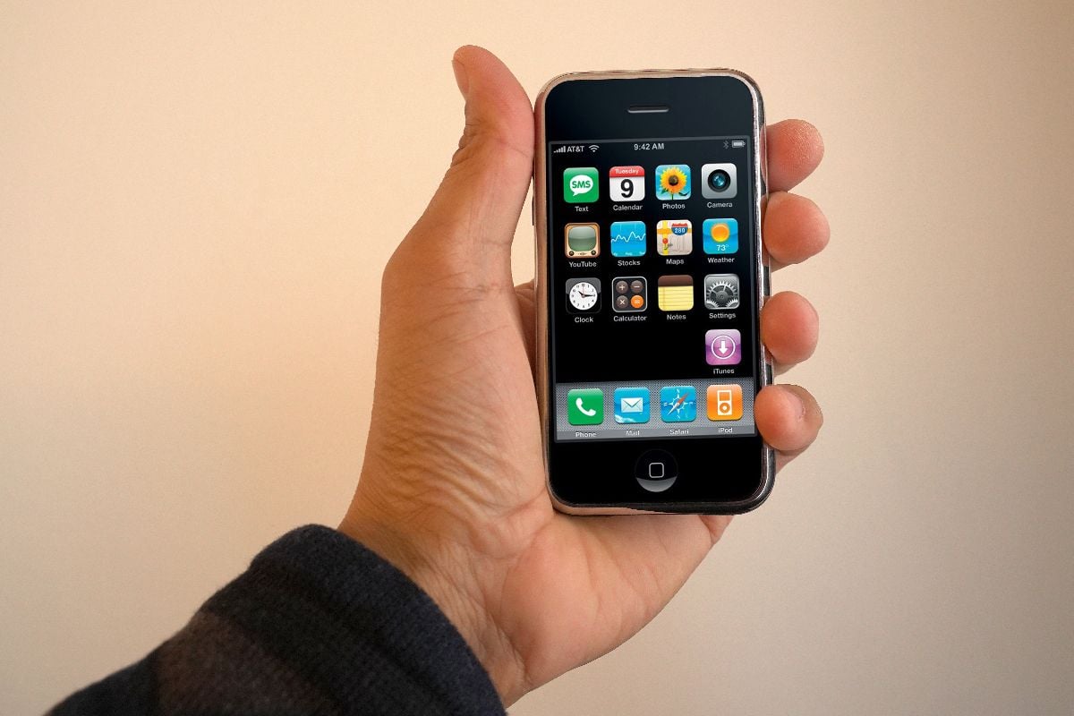 A male hand holding a 1st generation iPhone.