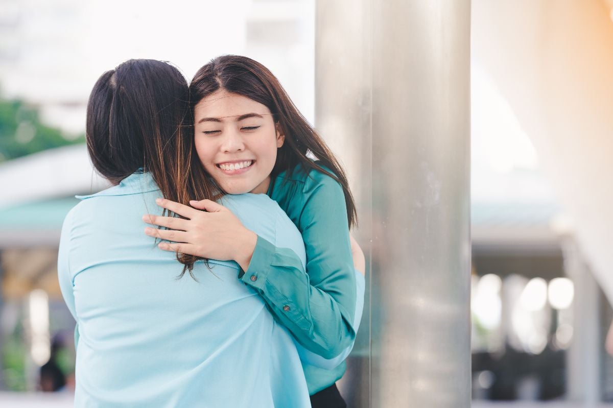 Friends hugging goodbye outdoors.