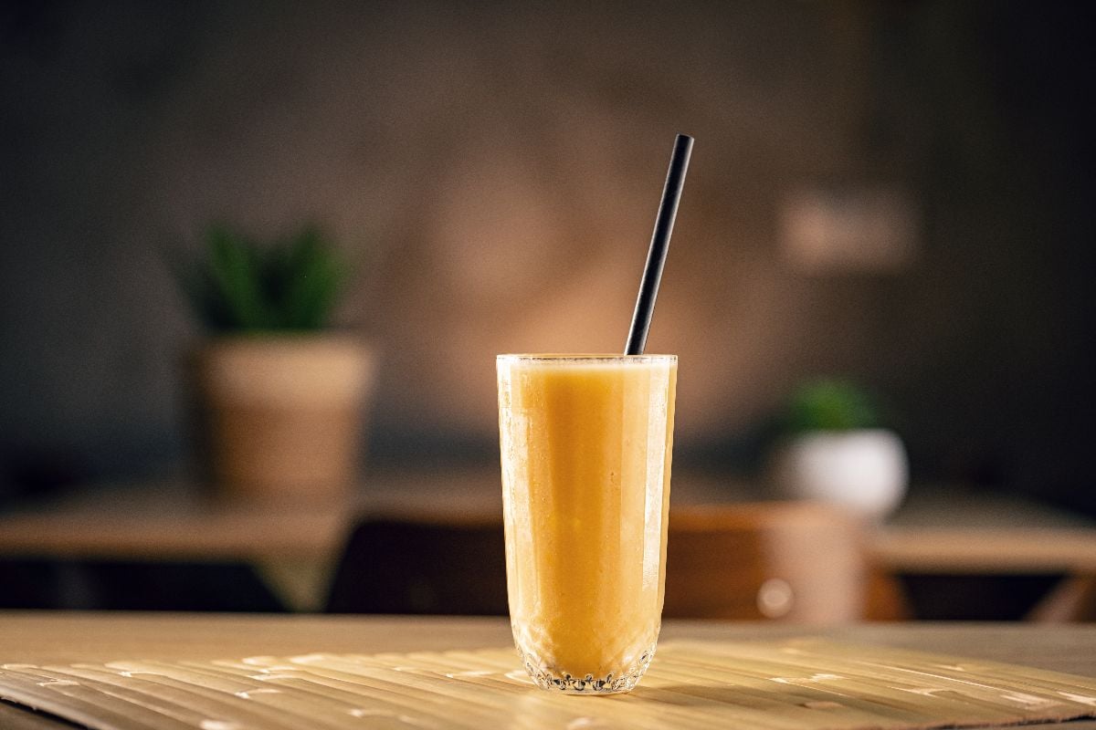 Refreshing yellow smoothie standing on a table in a cafe.