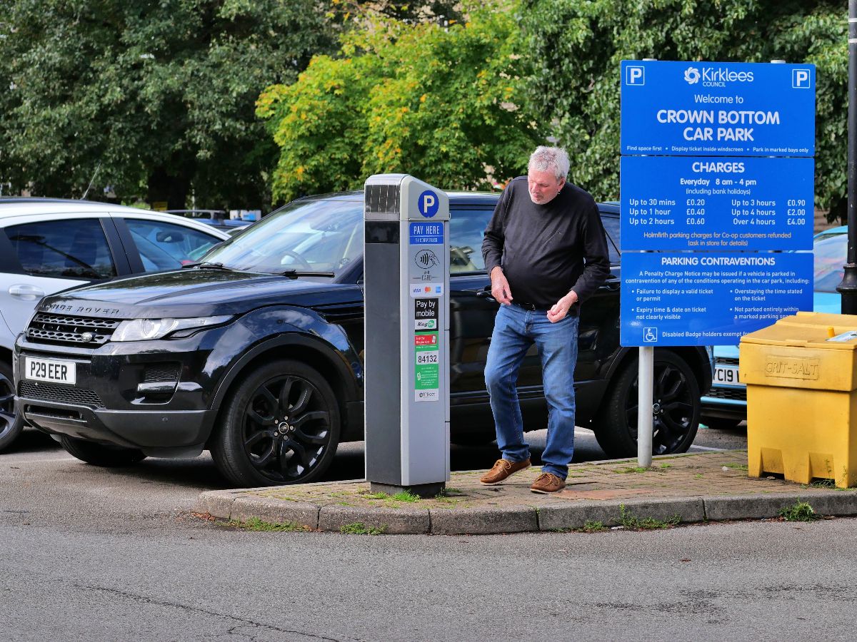Man looking on a pay parking kiosk.