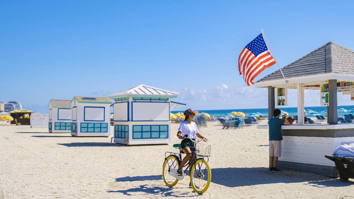Woman on the beach in Miami riding a bicycle.