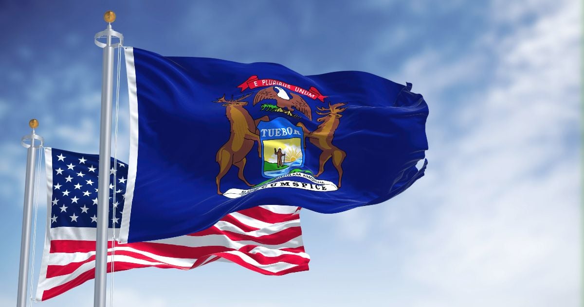 The Michigan state flag waving along with the national flag of the United States of America. 