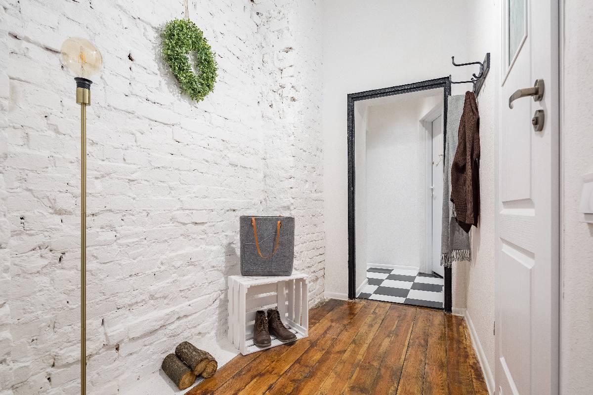 Industrial-style mudroom with white brick wall and rustic hardwood flooring