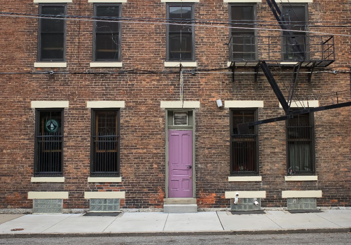 A brick building with a purple door and a fire escape.