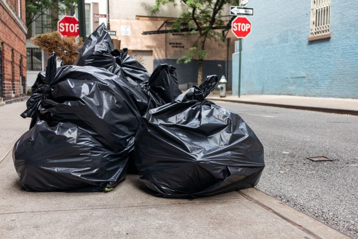 Black trash bags along a street and sidewalk in Greenwich Village of New York City.