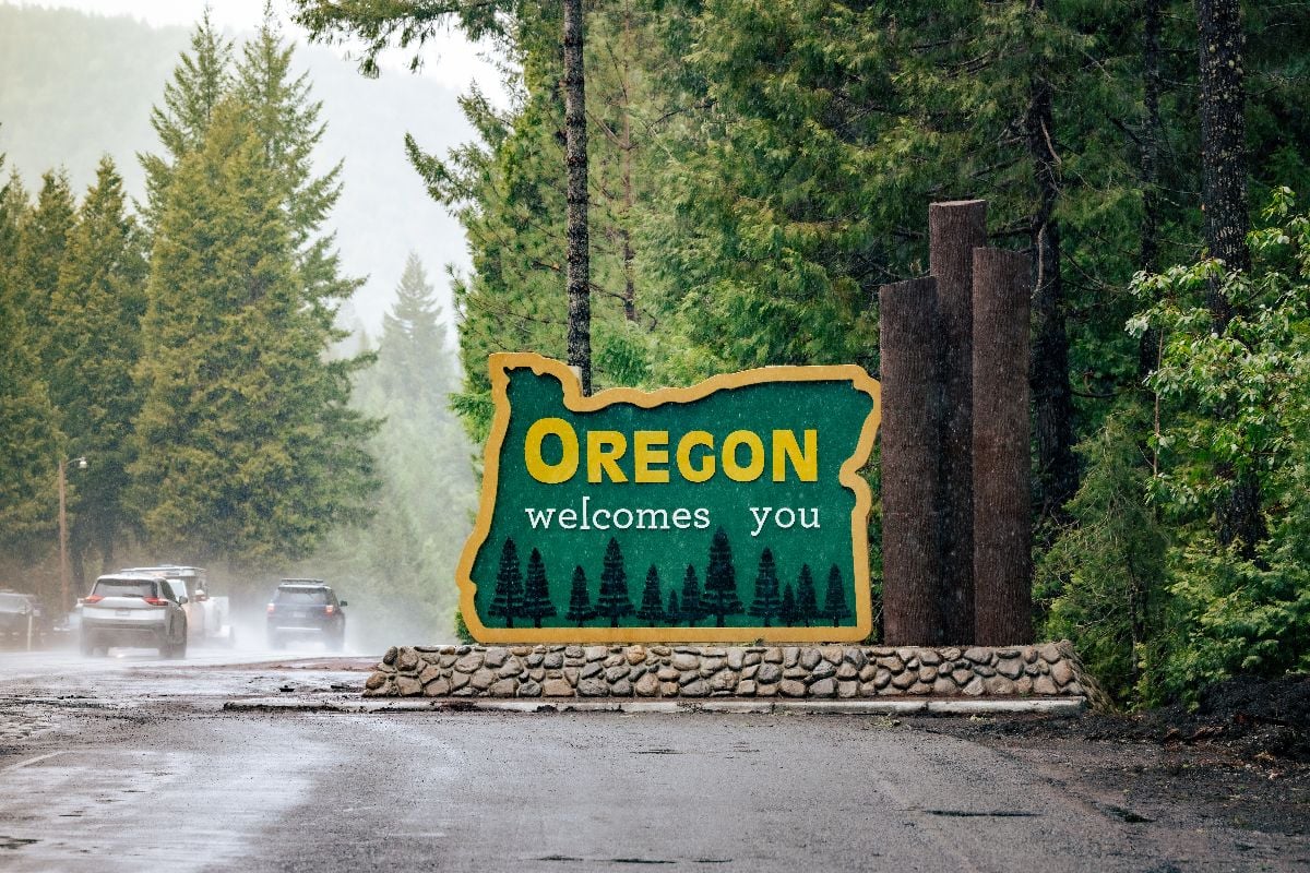 Oregon welcomes you sign at state line during rainy season.