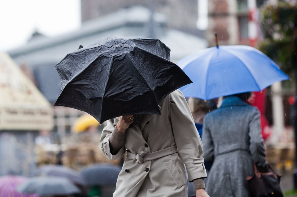 People walking with umbrellas and fighting against the wind.
