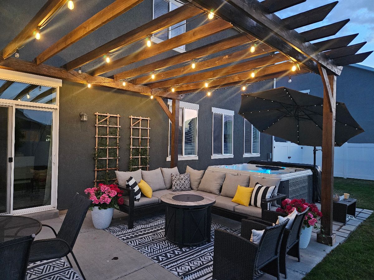 An outdoor patio with a grey L-shaped couch and a fire pit.
