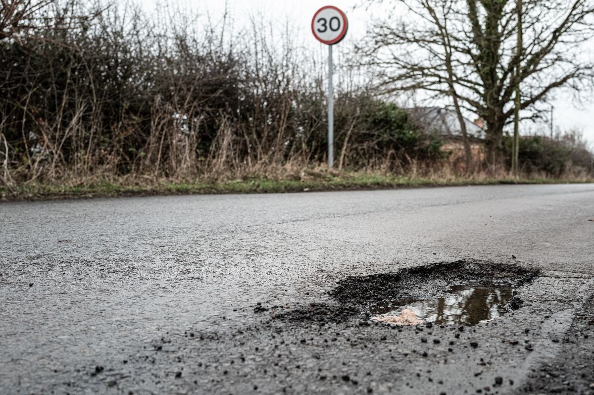Deep road pothole filled with rainwater.