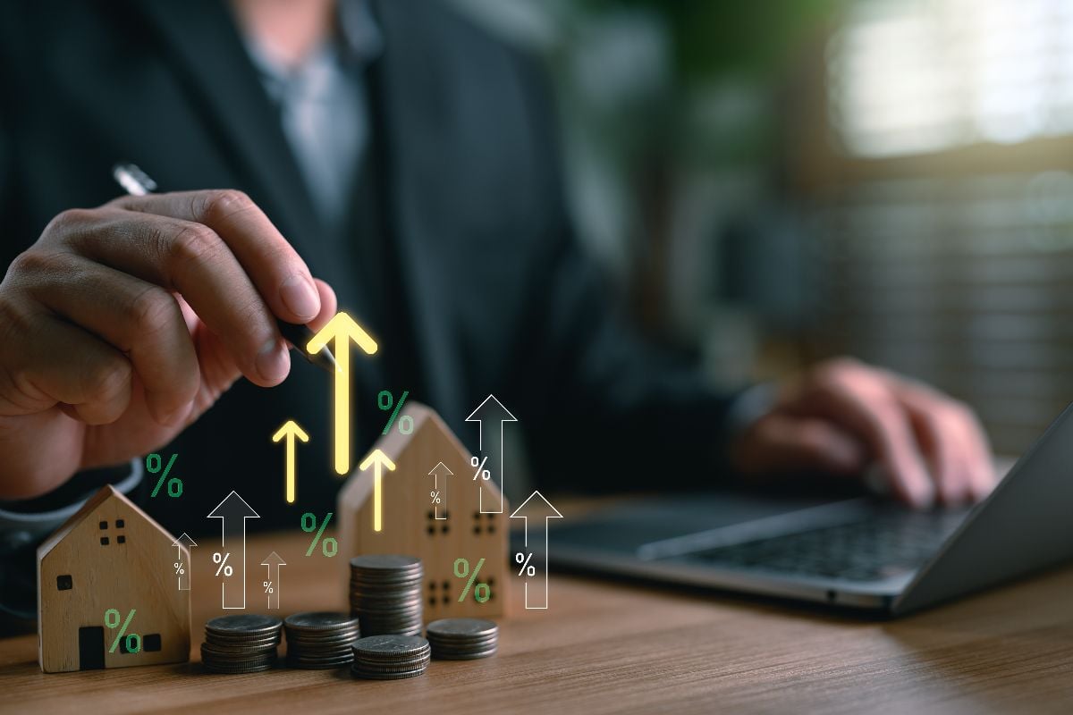 Real estate investor analyzing property value growth with stacked coins and miniature houses.