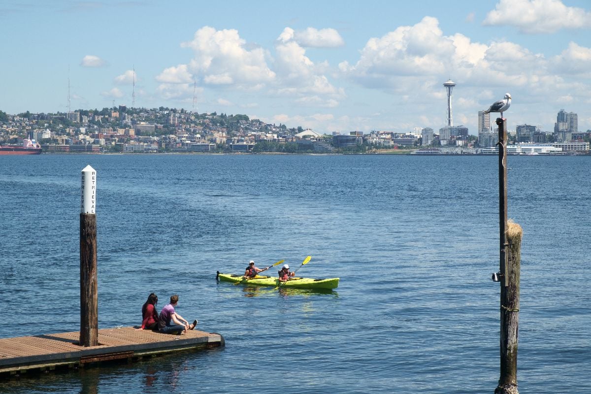 Couple in rental kayak pass before another couple sitting on dock.