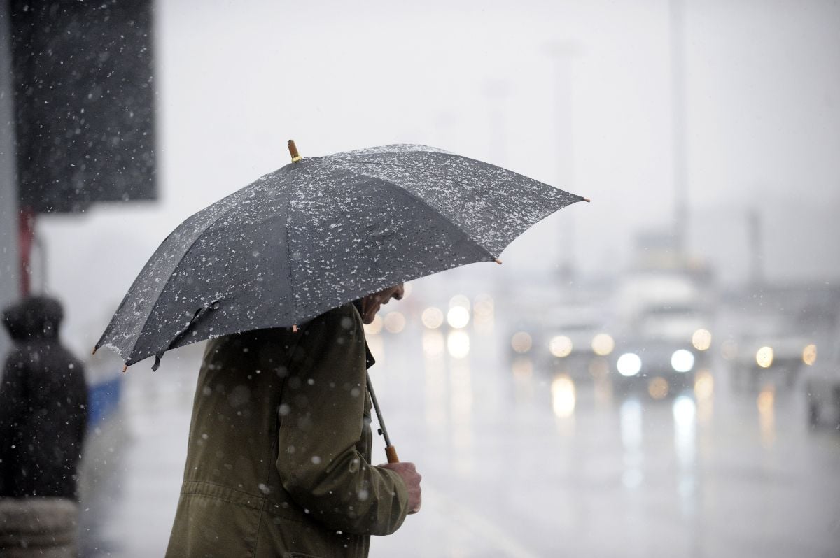 Man with an umbrella walking on the street.
