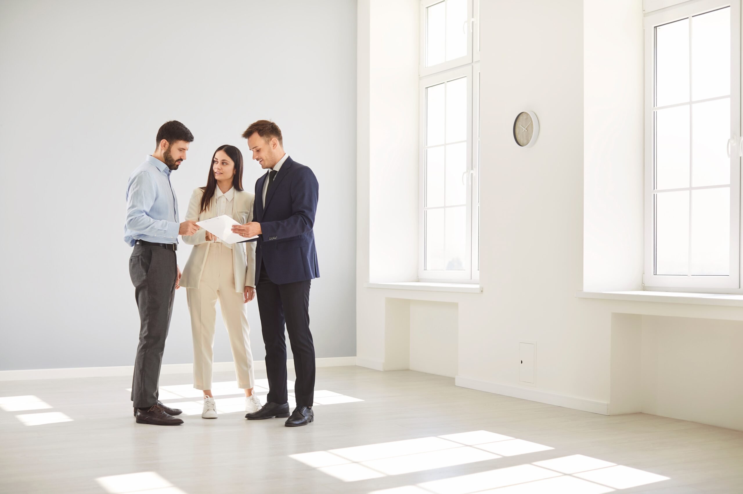 Real estate agent negotiating with a young couple inside an empty house.