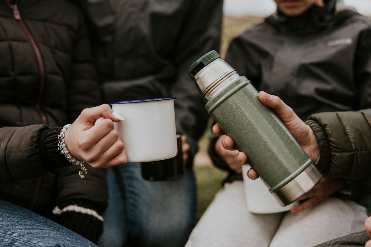 Friends holding stainless steel bottle and mug.