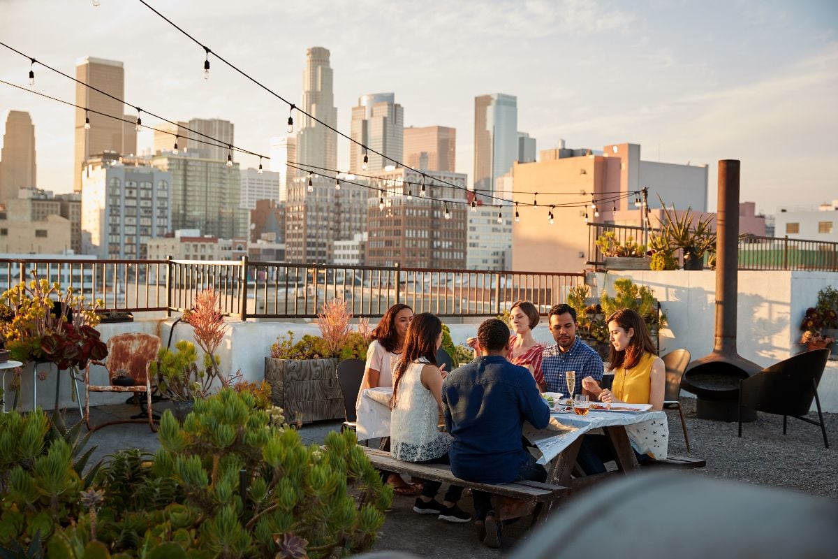 Friends gathered on rooftop terrace for meal.