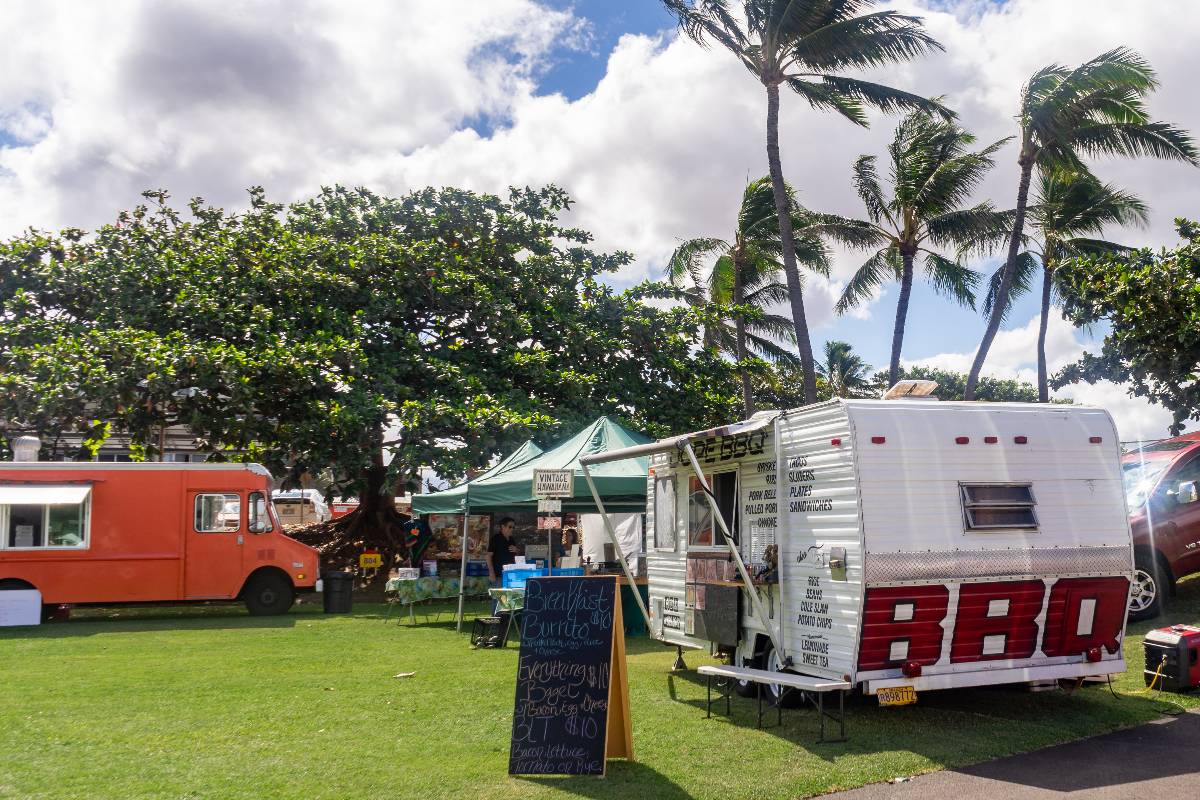 Food truck and RV trailer on the grass lawn of the Maui Swap Meet.