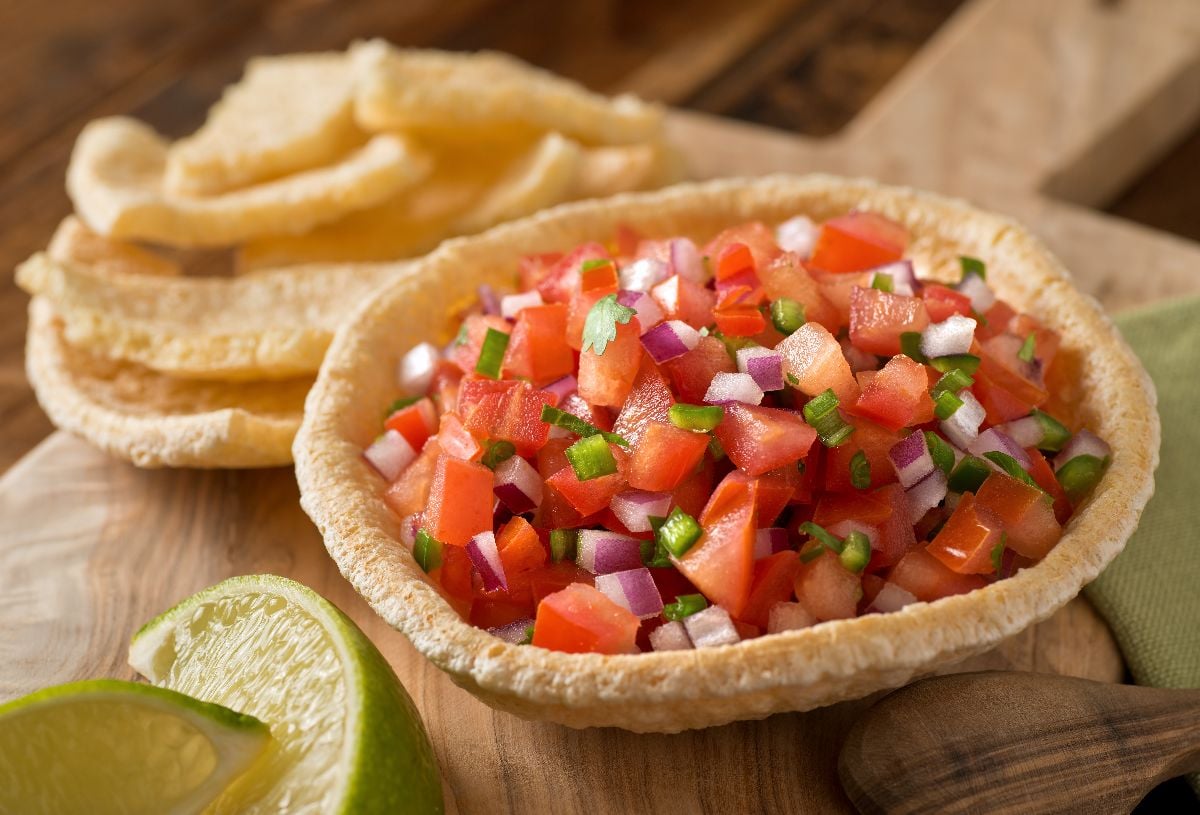 Fresh tomato salsa with serrano pepper, red onion, green onion, lime, and cilantro in a tortilla bowl.