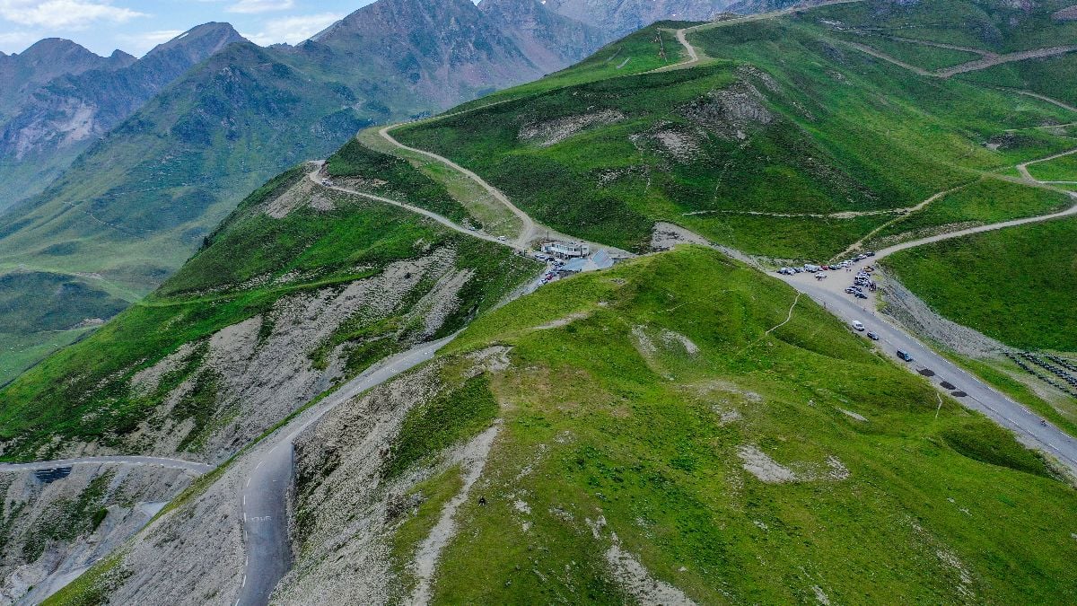 Mountain pass with winding roads and green hills.