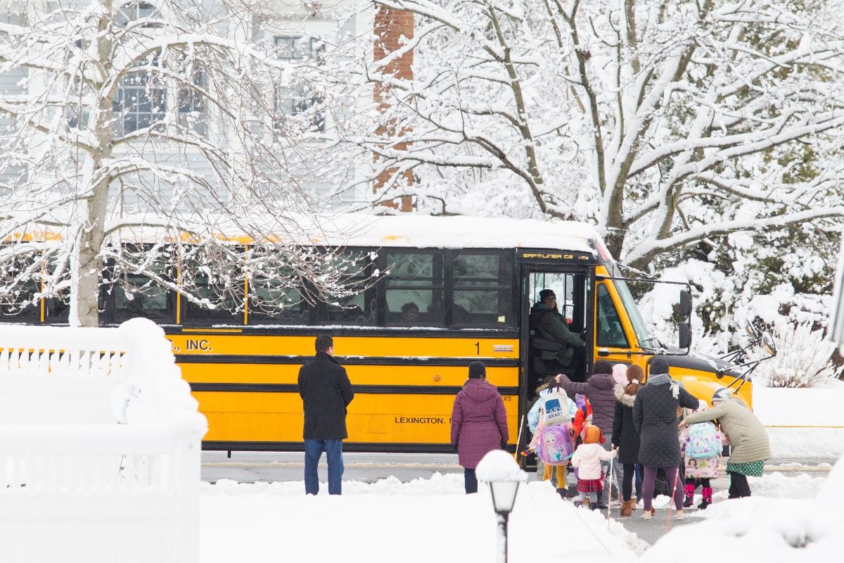 Children getting on the bus on a snow day.