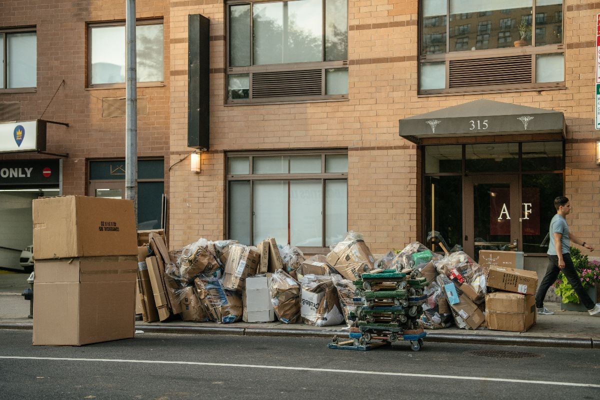 Large stacks of cardboard boxes and plastic trash bags piled on the sidewalk.
