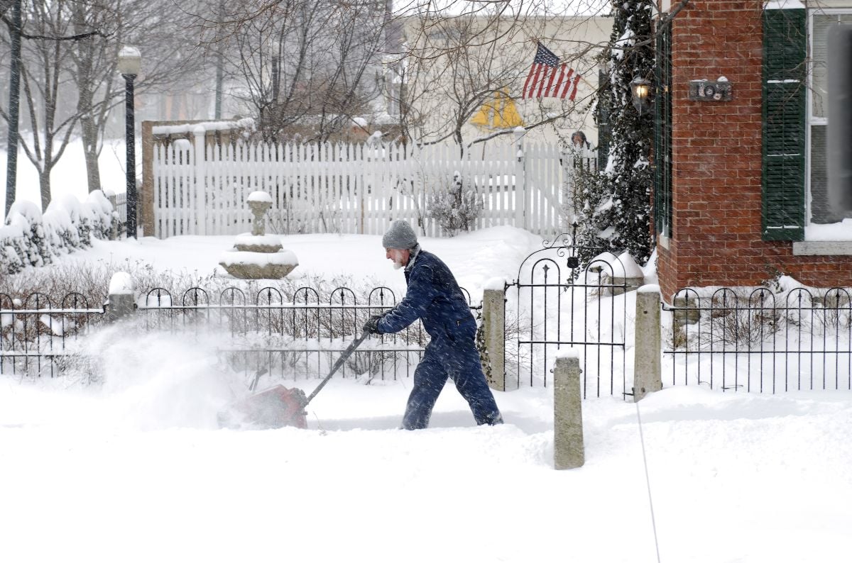 Man with snow blower digging out sidewalk.