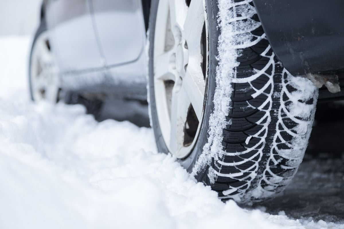 Close up of car tire covered with snow on a slippery road.