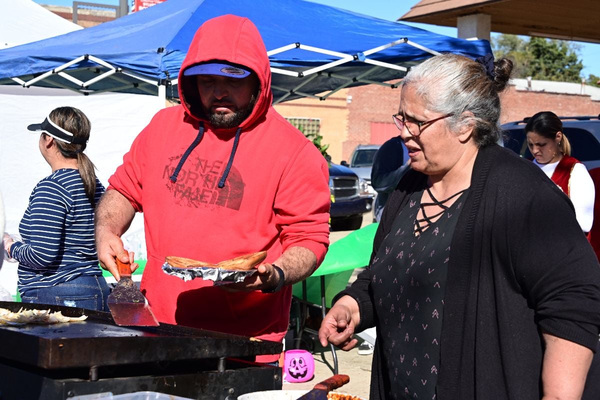Grandson learning under the tutelage of his Abuela how to cook grilled onions, peppers, and beef for fajitas.