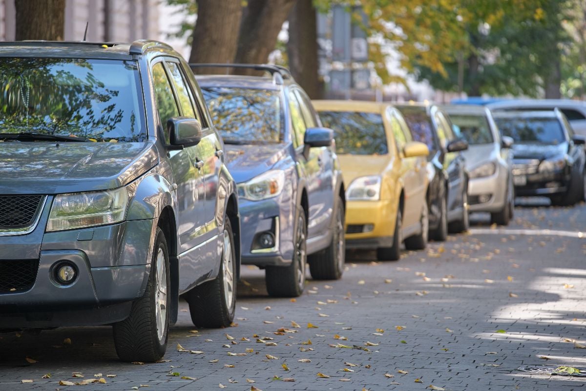 City traffic with cars parked in line on street side.