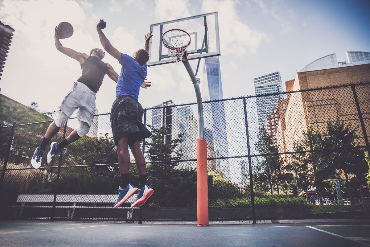 Two athletes playing basketball outdoors.