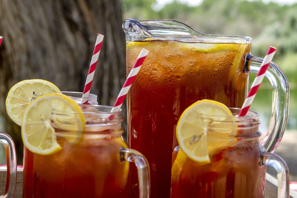 Pitcher and mason jar mugs filled with iced tea and lemons.