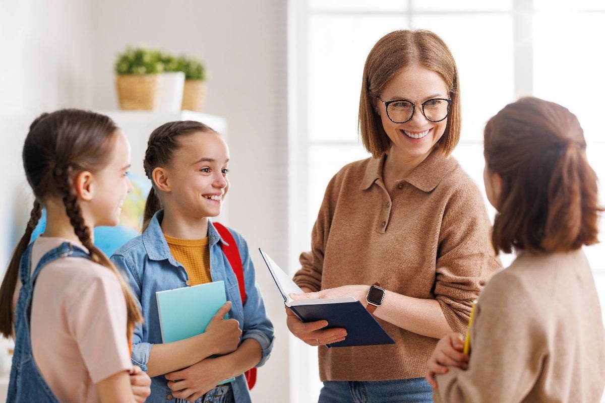 Teacher speaking with students in the classroom.