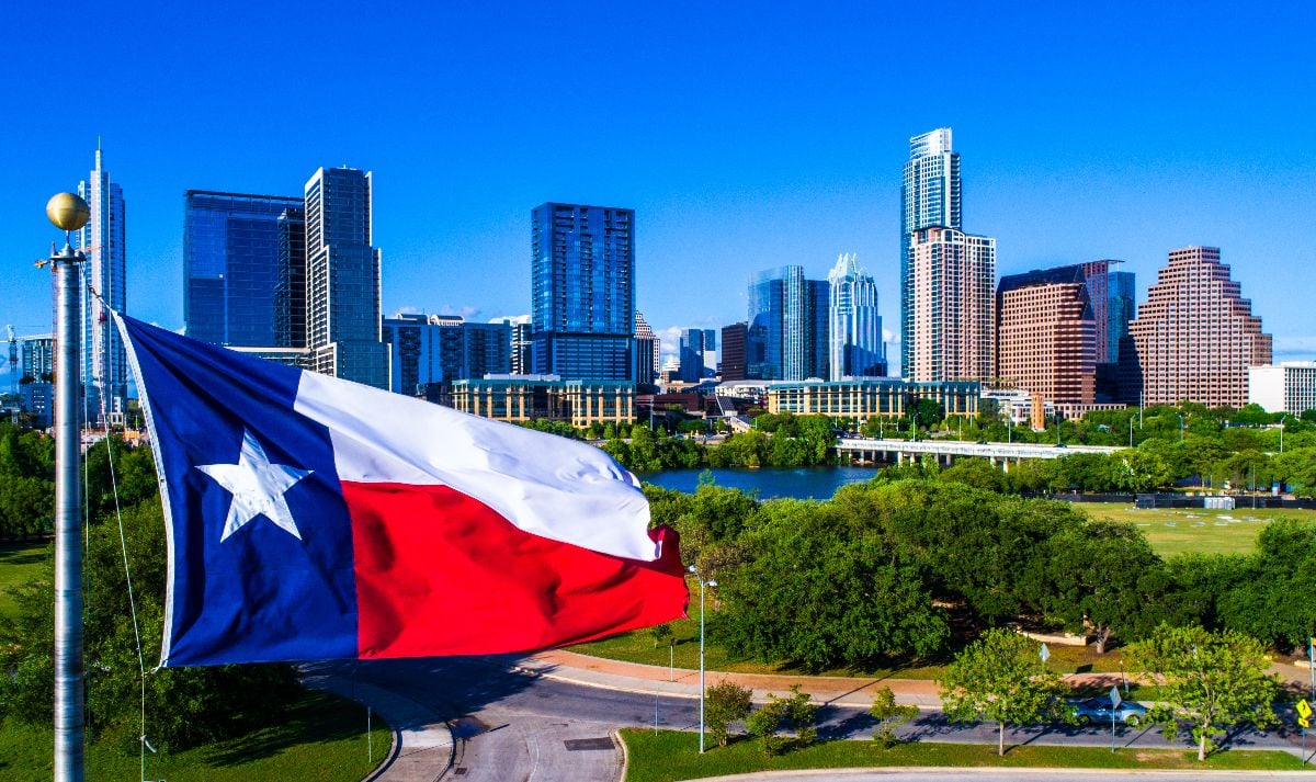 Texas flag waving in front of Austin, Texas skyline.