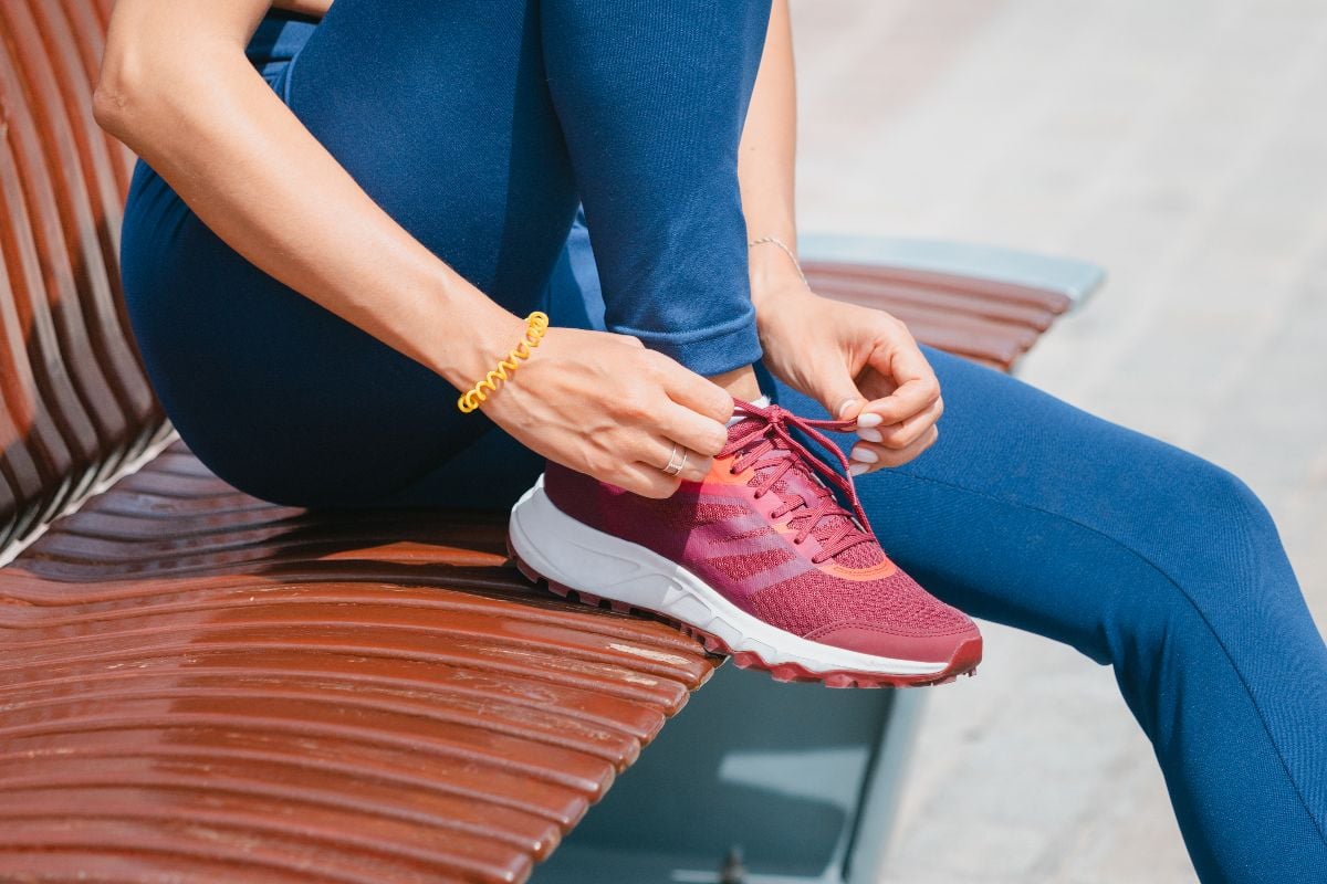 Woman ties her shoelaces on her running shoes .