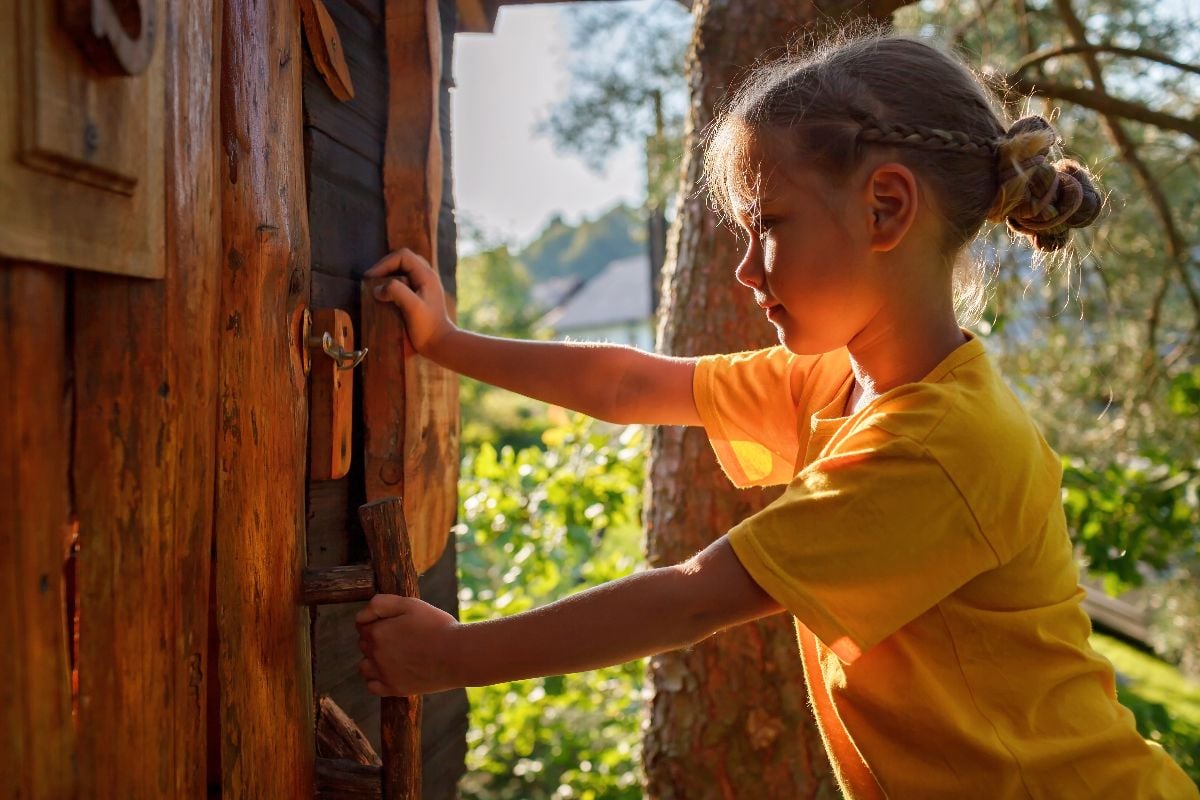 Girl opening the door of a tree house.