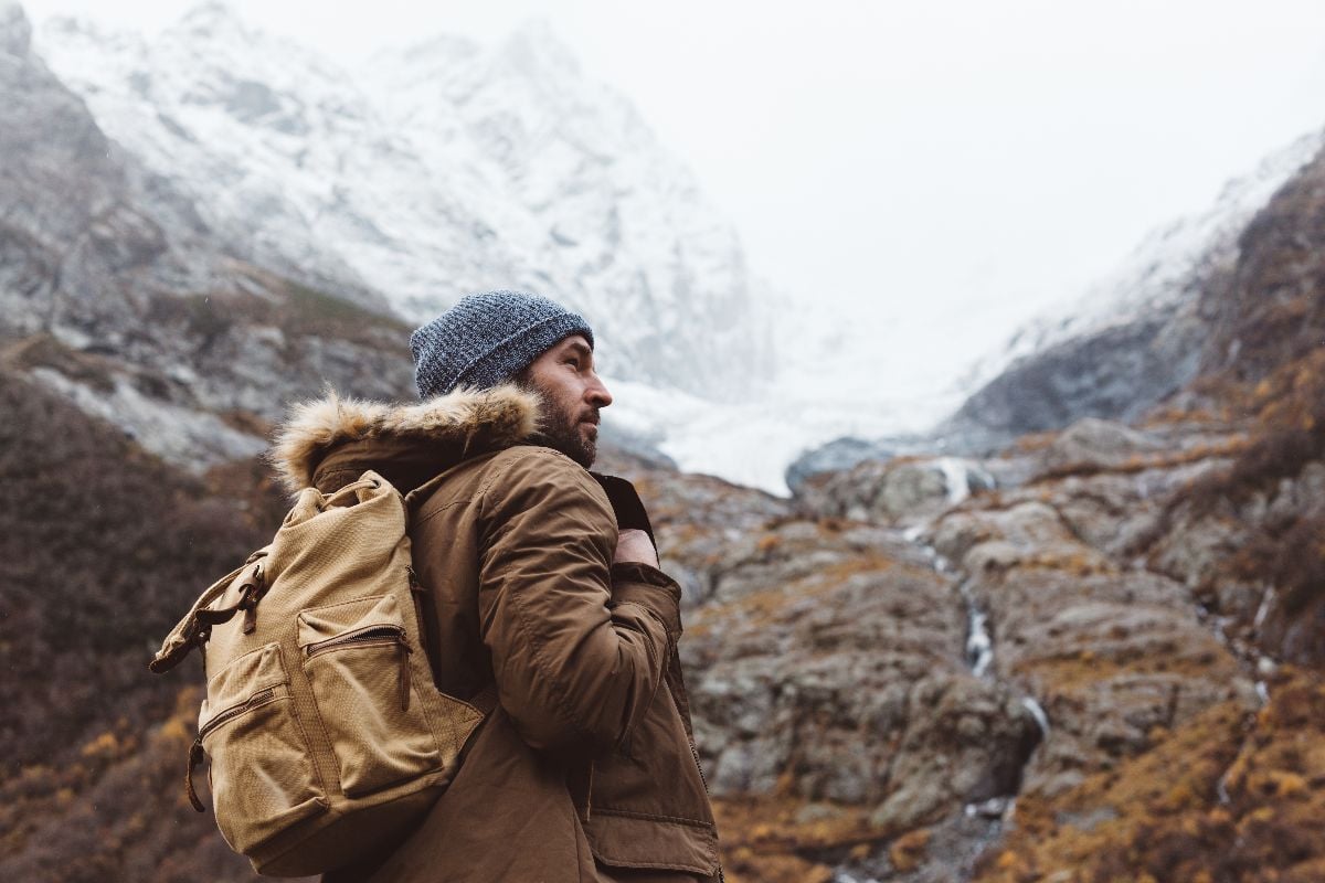 Man with backpack trekking in mountains.