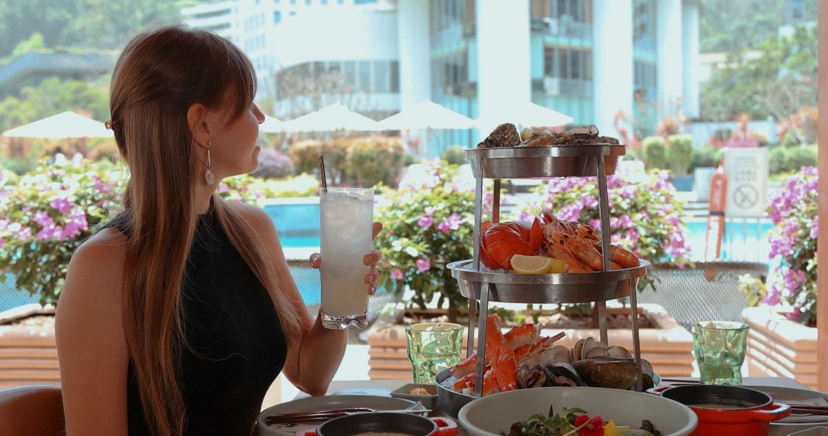 Woman enjoying seafood platter by poolside in upscale restaurant.