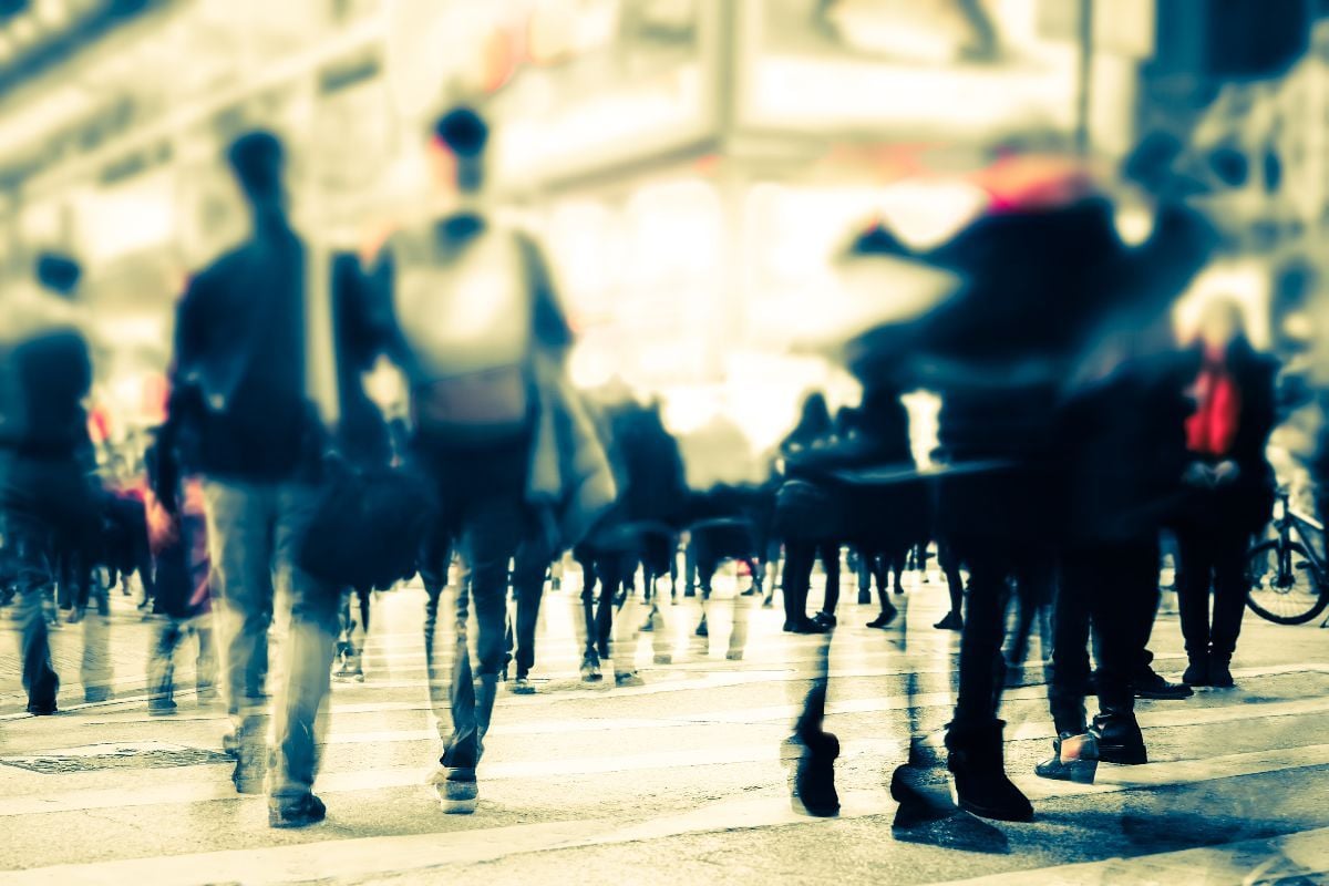 Blurred image of people moving in crowded night city street.