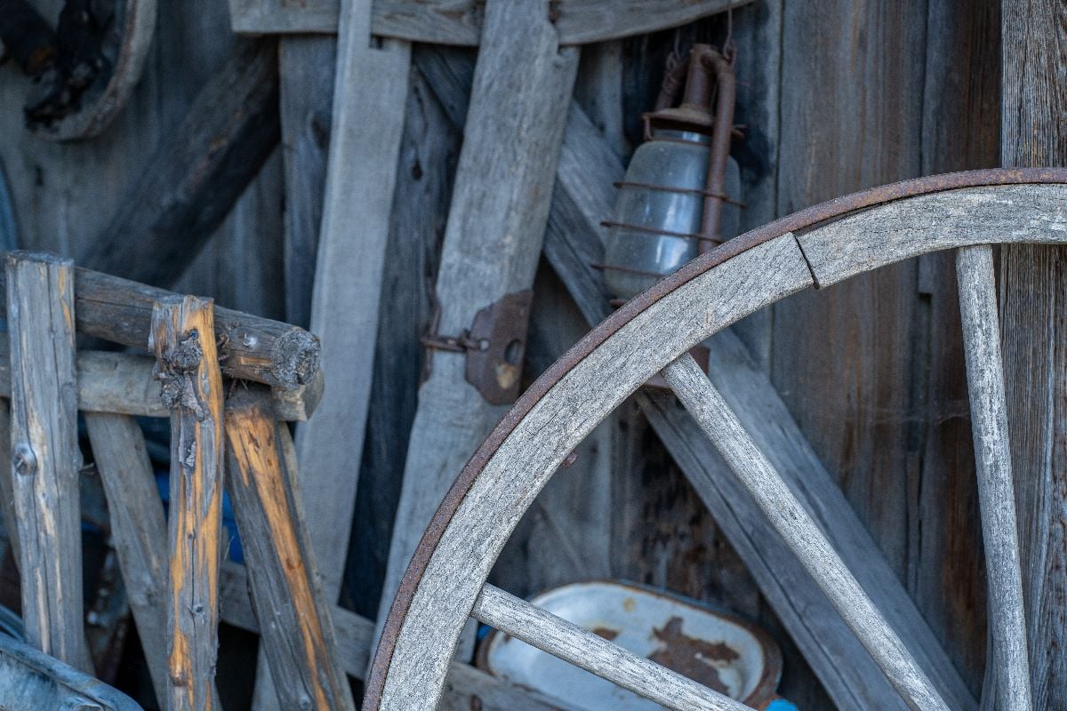 Wooden wagon wheel in a rustic storage area.